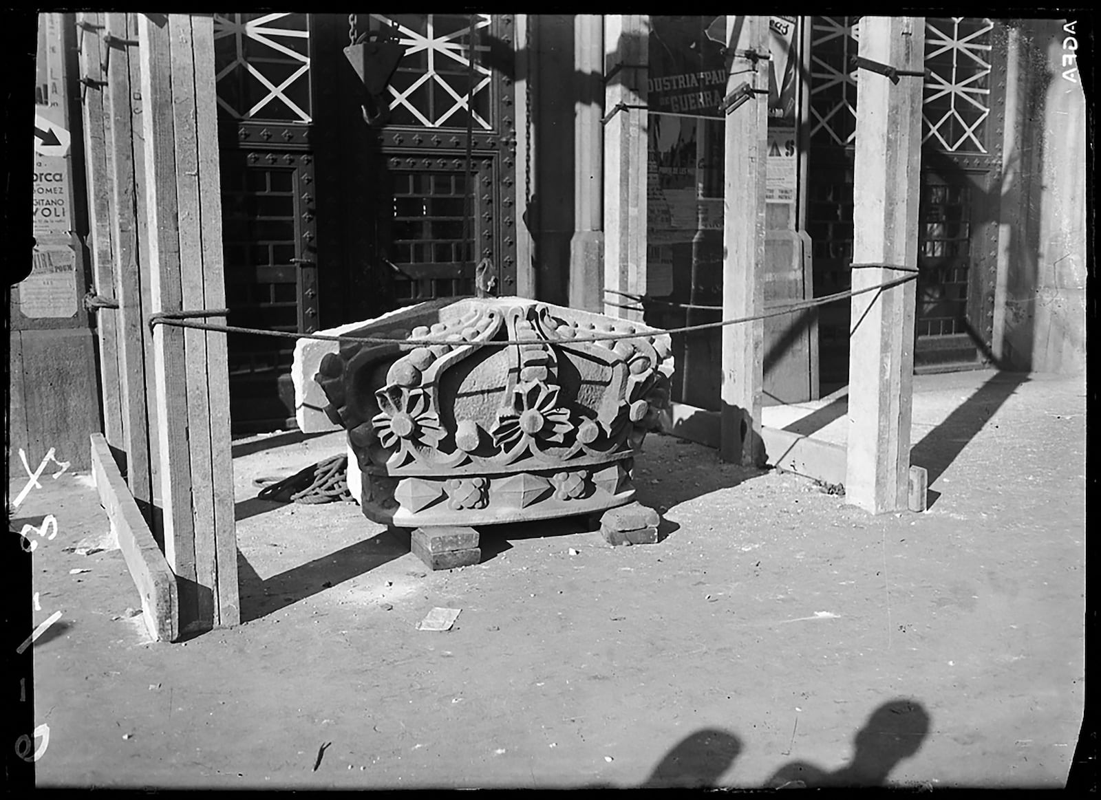 Una corona de pedra de la façana de l'edifici seu de la Universitat de Barcelona resta sobre el paviment després d'haver estat enderrocada. Gener de 1937. Fotografia de Pérez de Rozas. AFB