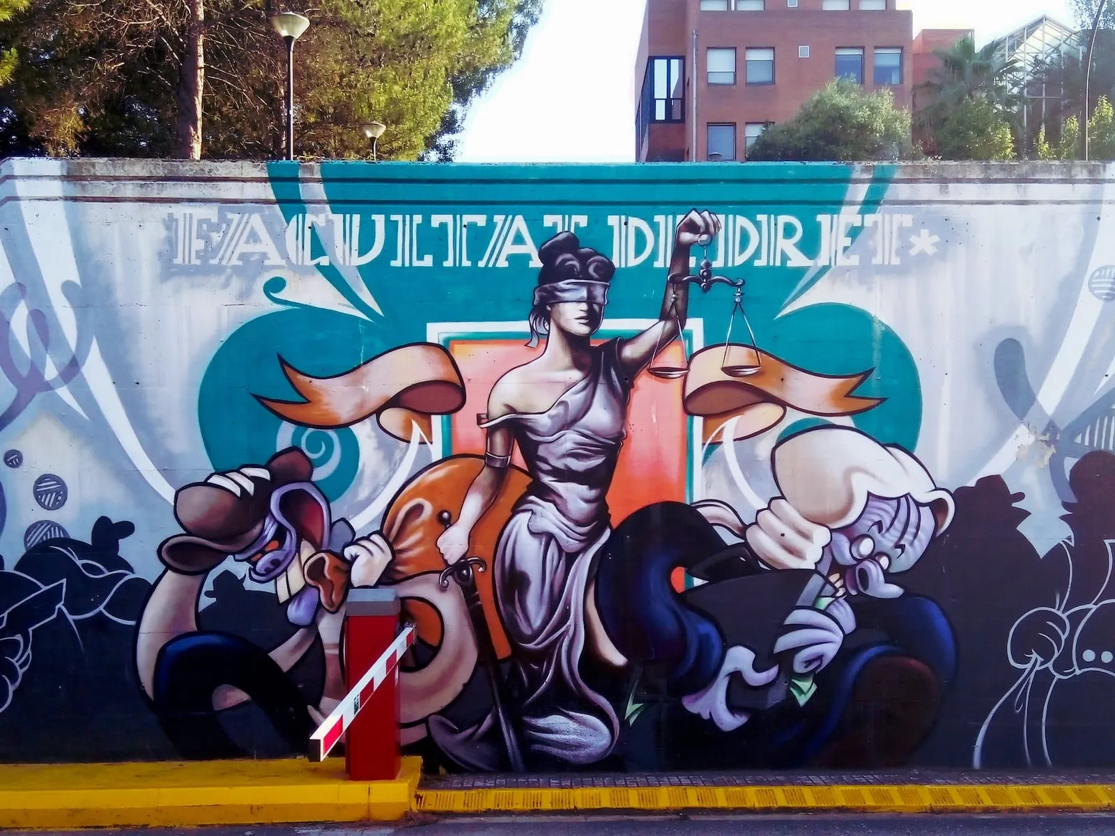 Grafit a la Facultat de Dret de la Universitat Autònoma de Barcelona fet l’any 2019 per Kram Skum que representa la justicia enmig d'un lladre i un banquer corrupte. Fotografia de Docosong