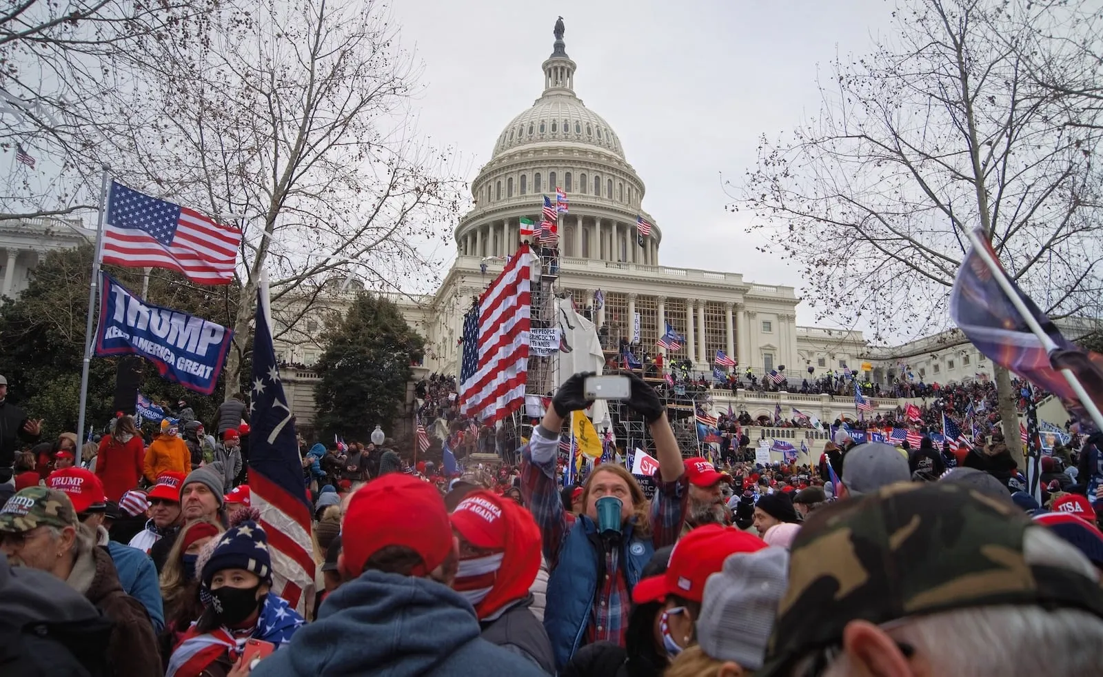 Exterior del Capitoli dels Estats Units durant l'atac del 6 de gener de 2021 a l'edifici amb manifestants portant banderes i el lema "Make America Great Again". Fotografia de Tyler Merbler